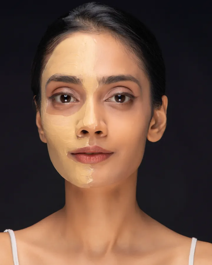 A woman with multani mitti on one half of her face and clean skin on the other