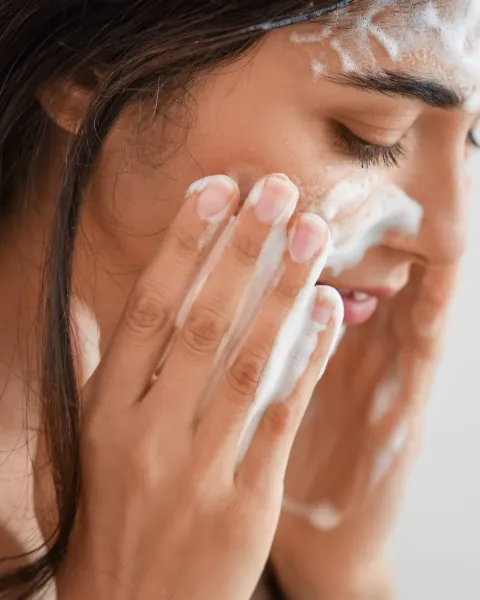 A woman washing her face with a foaming cleanser