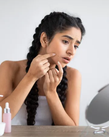 A woman leaning in to check a spot on her cheek