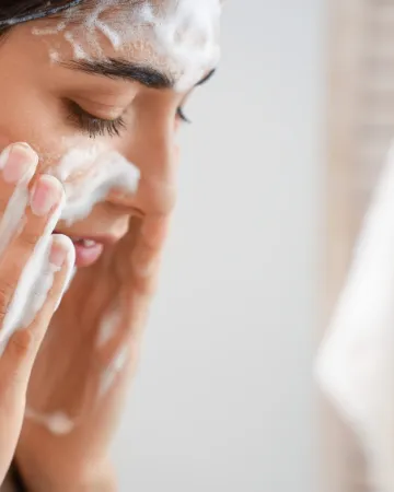 A woman working a face wash into a lather